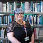 Bobby standing in front of library shelves of books